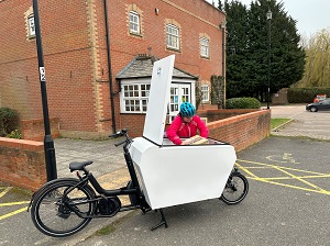 Woman delivering parcels with cargo bike opeing at the top