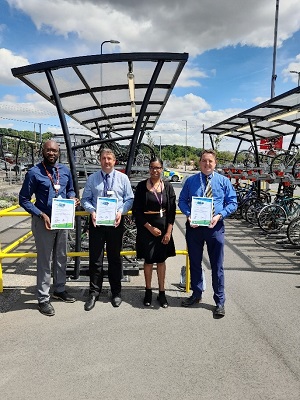 Four train stations employees standing by bike stands