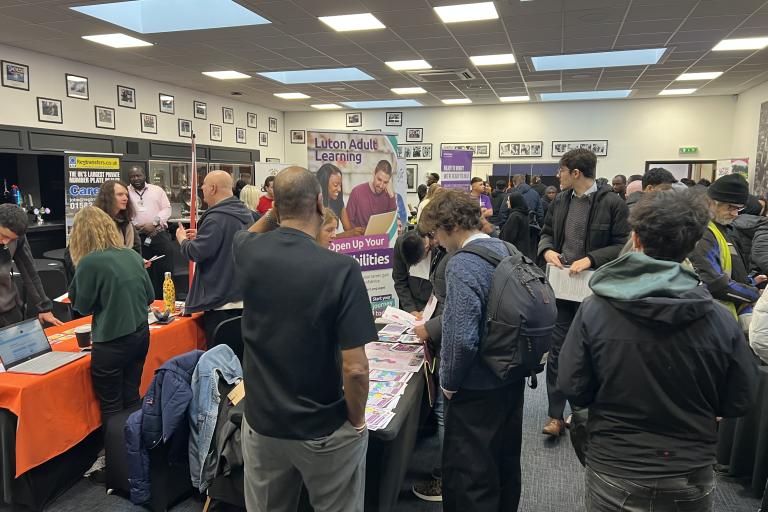 previous job fair showing exhibitor stands and attendees talking to employers