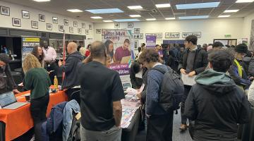 previous job fair showing exhibitor stands and attendees talking to employers