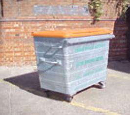 A large metal trade waste bin with an orange lid